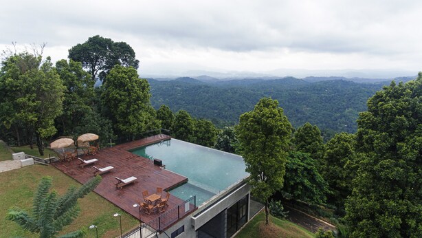 Una villa moderna con piscina infinita en la azotea que domina un paisaje montañoso.