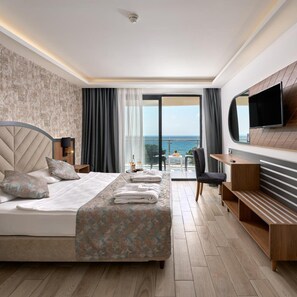 Une chambre d’hôtel avec un lit, un bureau, une chaise, une télévision et une vue sur la mer.