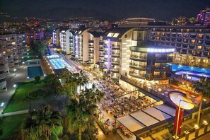 A hotel with multiple floors, a swimming pool, and outdoor dining areas. - grand uysal (alanya tosmur)