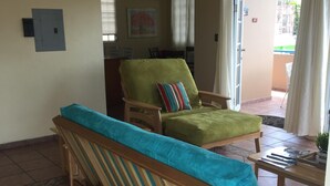 Ein Wohnzimmer mit Holzsofa und Sesseln, einem kleinen Tisch und Blick ins Freie.