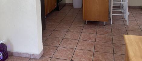 A kitchen with a microwave, stove, and cabinets. There is a ceiling fan and a window with blinds.