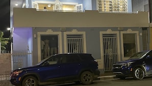 Ein zweistöckiges Gebäude mit einem Balkon im oberen Geschoss, mit mehreren Fenstern und einer Tür.