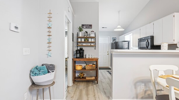 A modern kitchen with white cabinets, a wooden island, and a hanging light fixture.