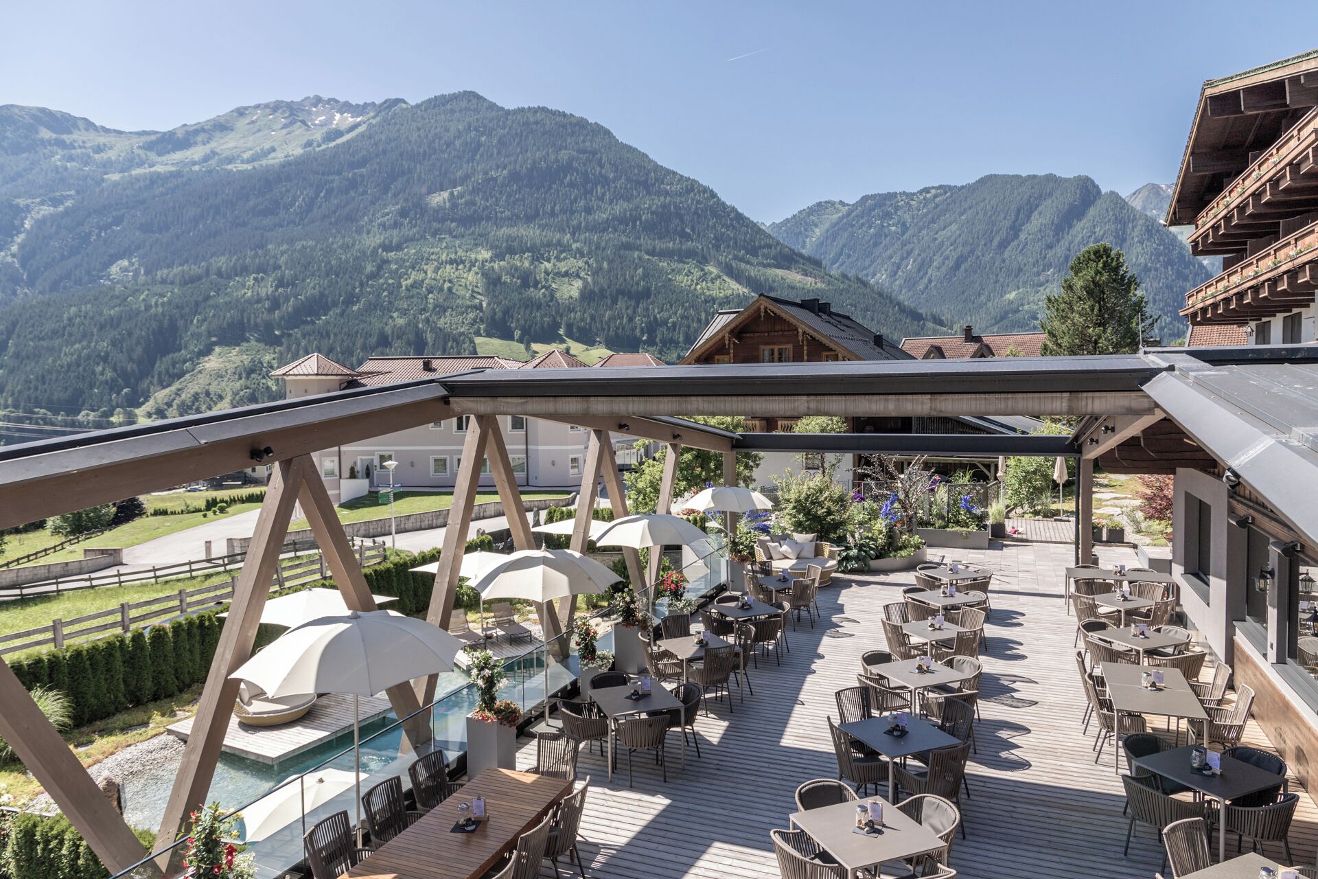 Une terrasse avec des sièges extérieurs et une piscine, offrant une vue sur un paysage montagneux.