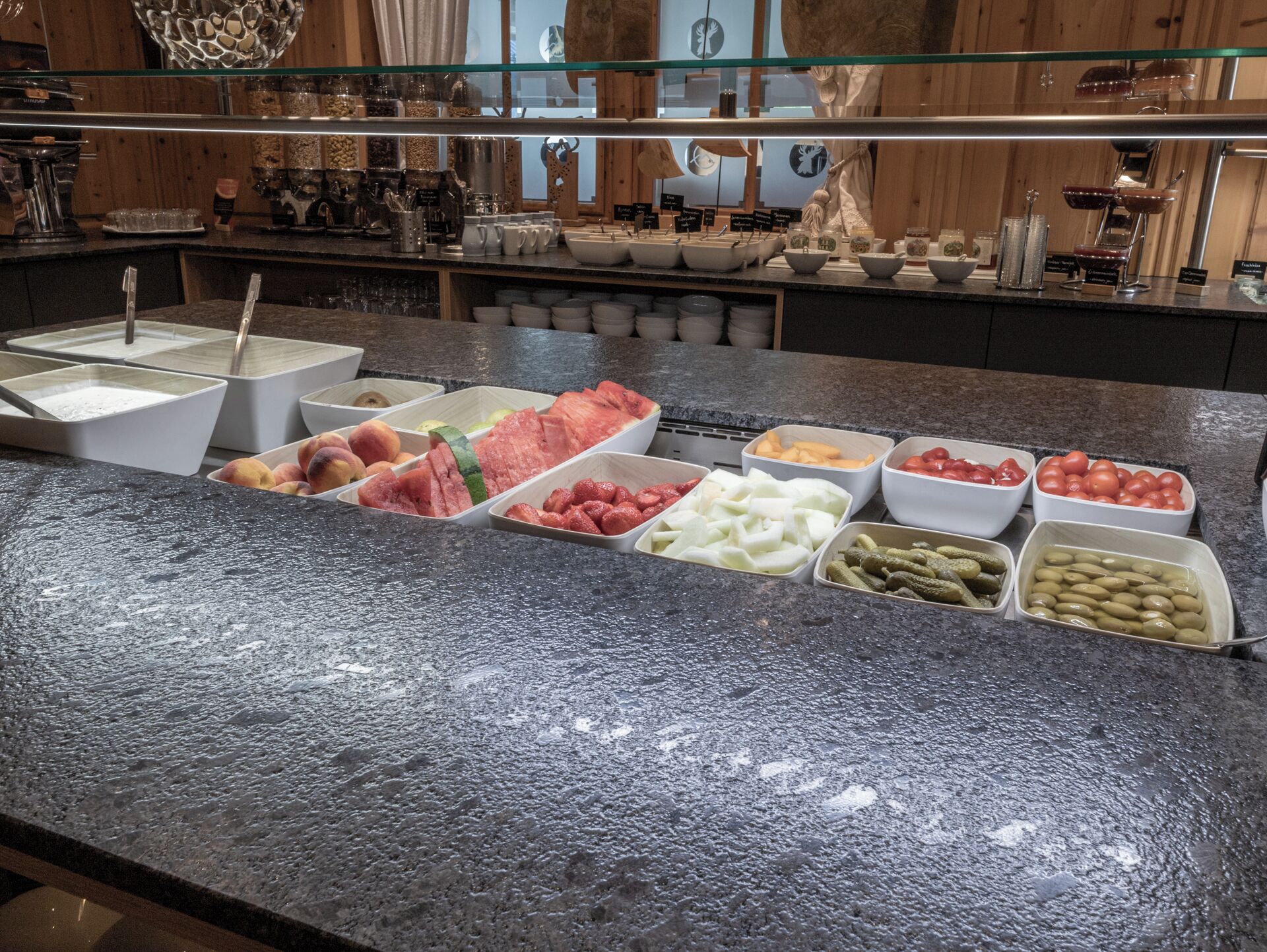 A buffet with various food items including fruits, vegetables, and condiments.