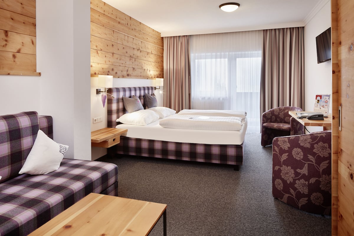 Una habitación de hotel con cama, sofá, escritorio y televisor.