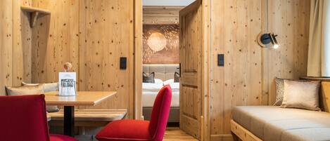 A wooden-paneled room with a bed, a table with chairs, and a wall-mounted light fixture.