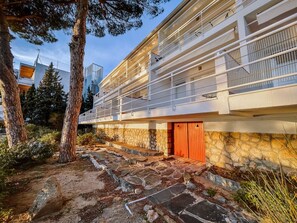 Un bâtiment moderne avec une façade en pierre, une porte en bois et un balcon doté de rampes en métal.