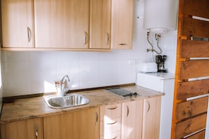 A kitchen with wooden cabinets, a stainless steel sink, a coffee maker, and a water heater. - Agi Marina 6 Apartamento for rent in Roses Girona. (Roses)