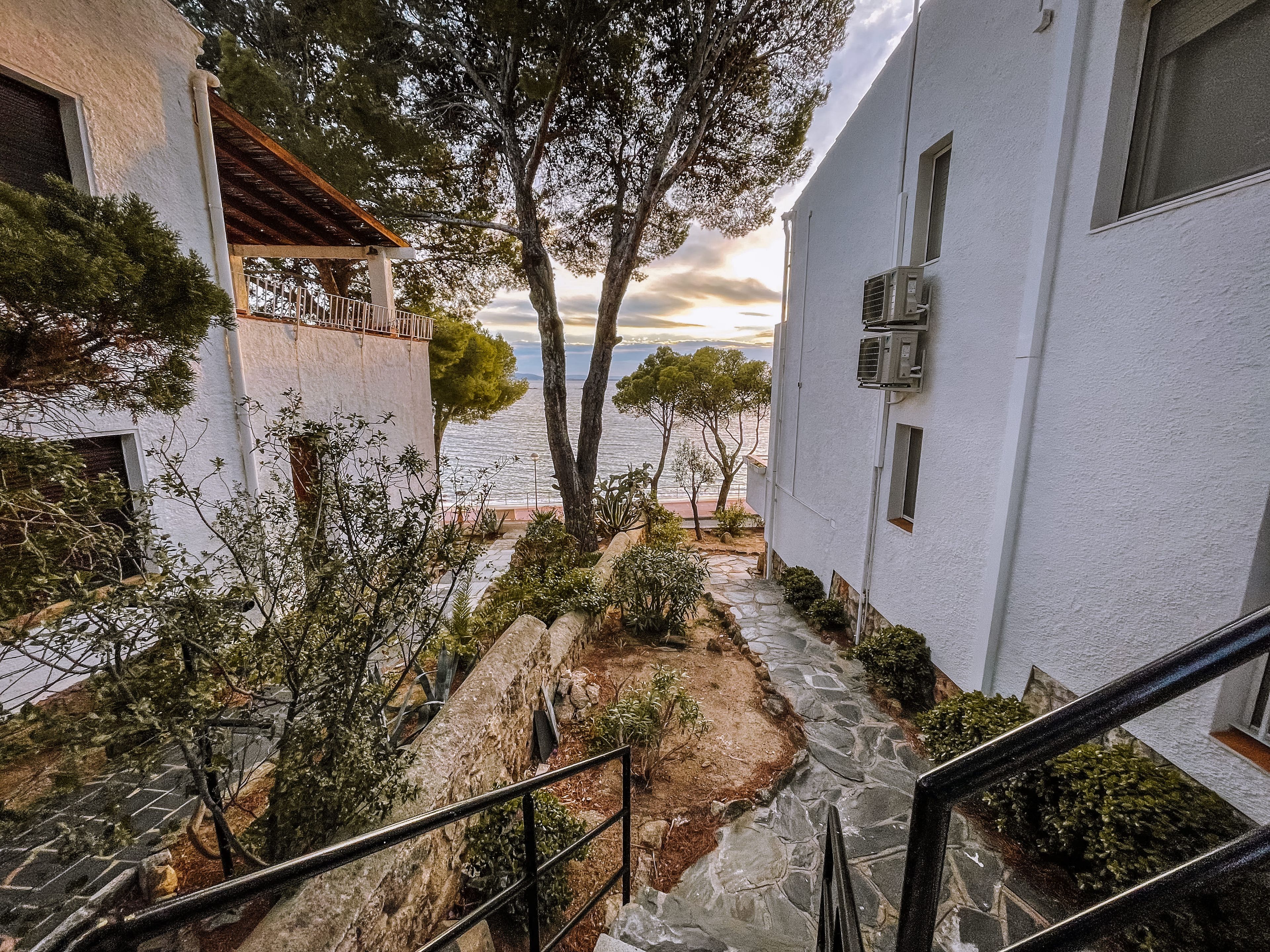 A coastal building with a stone pathway leading to a terrace overlooking the sea.
