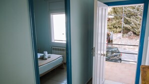 Una habitación con cama, ventana y puerta que da a un espacio exterior.