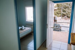 Une pièce comprenant un lit, une fenêtre et une porte donnant sur un espace extérieur.