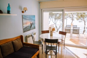 Une pièce comprenant un canapé, une table avec des chaises, un tableau, une lampe et une vue à travers une porte vitrée.