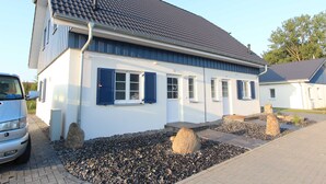 Ein zweistöckiges Haus mit einem Ziegeldach, einer Auffahrt und einem Kiesplatz mit Steinen.