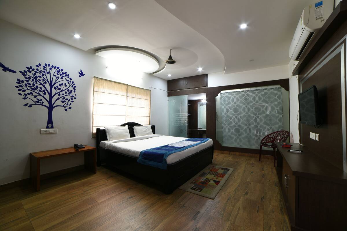 A modern bedroom with a bed, bedside table, and a wall-mounted TV.