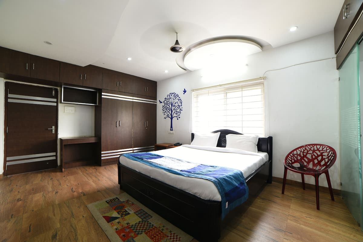A bedroom with a bed, wardrobe, and a chair.