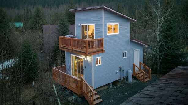 Une cabane à deux étages dotée d’un balcon, d’une terrasse et offrant une vue sur les montagnes.