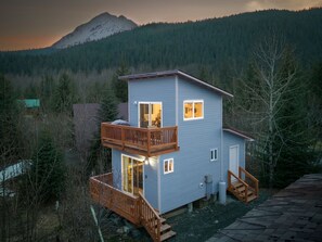 Une cabane à deux étages dotée d’un balcon, d’une terrasse et offrant une vue sur les montagnes.