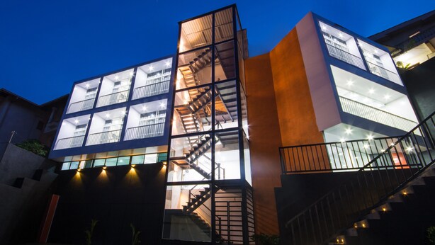 Un edificio moderno con varios pisos, amplias ventanas y una escalera central.