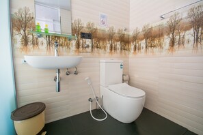 A bathroom with a white sink, toilet, and a trash bin. - Avora Hotel (Kandy)