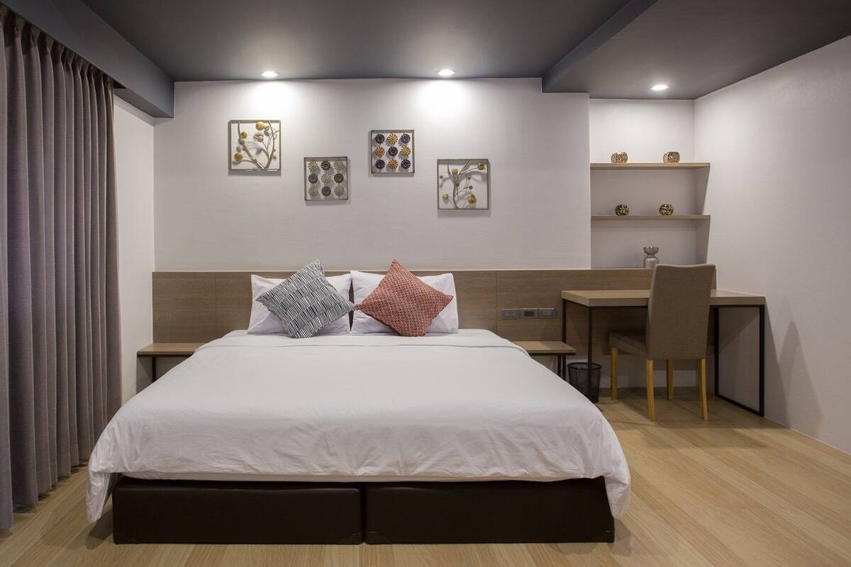 A modern bedroom with a large bed, a desk, and a chair.