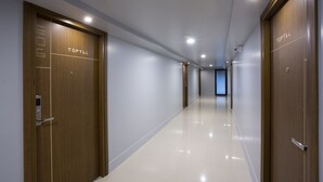 A modern hotel corridor with wooden doors labeled "TOPTEL" and a shiny, reflective floor. - Toptel Thaphra (Bangkok)