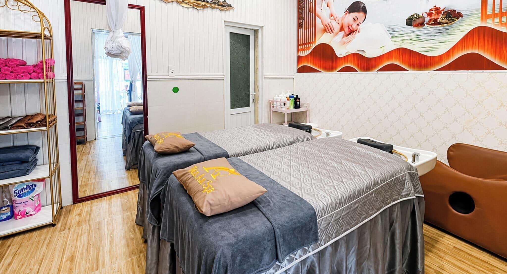 Ein Zimmer mit zwei Betten, einem Massagesessel, einer Ablage für Toilettenartikel und einem Wandbild.