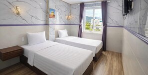 Ein Hotelzimmer mit zwei Betten, einem Nachttisch, einem Fenster mit Vorhängen, Marmorwänden und Blick auf Gebäude.