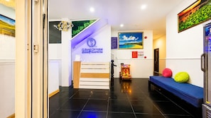 A hotel reception area with a reception desk, a blue sofa, and a painting on the wall. - Q Song Chi Con Dao Hotel (Ho Chi Minh City)