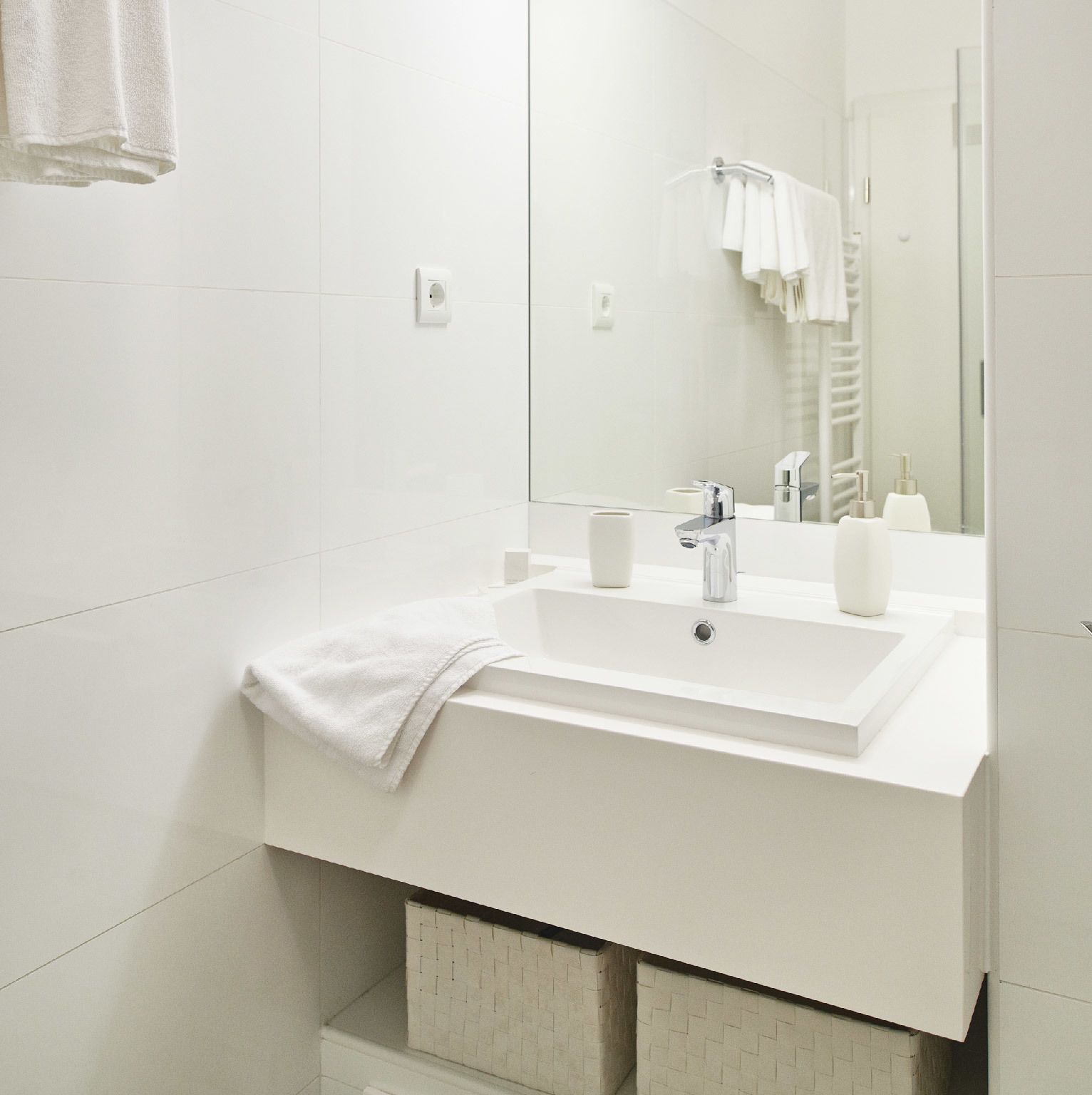 A modern bathroom with a white sink, mirror, and towel rack.