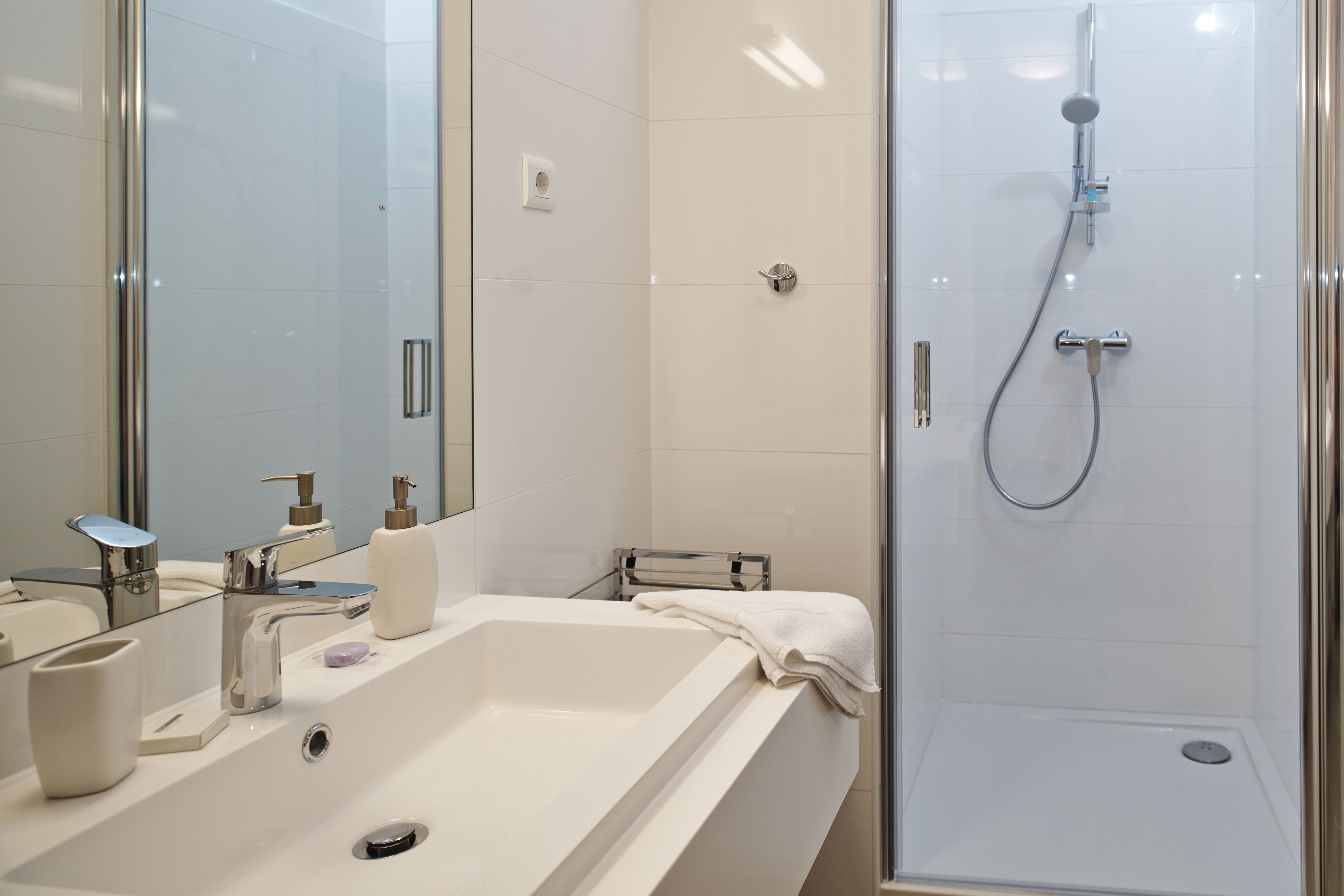 Ein modernes Badezimmer mit einem großen Waschbecken, einem Spiegel und einer Dusche.