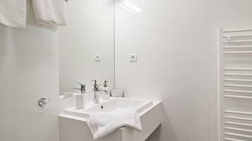 Une salle de bain moderne avec un lavabo blanc, un miroir et un porte-serviettes.
