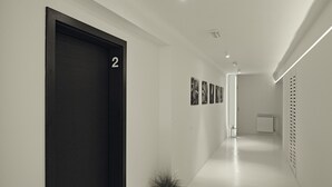 A modern hallway with a dark door labeled "2", a potted plant, and a series of framed pictures on the wall. - Design Studios SVI-MI (Zagreb)