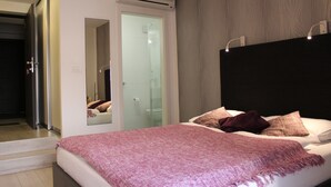 A modern bedroom with a large bed, a walk-in closet, and a bathroom visible through an open door. - Design Studios SVI-MI (Zagreb)