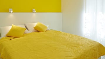 Un lit avec une couette et des oreillers jaunes, une tête de lit blanche et un mur d’accent jaune.