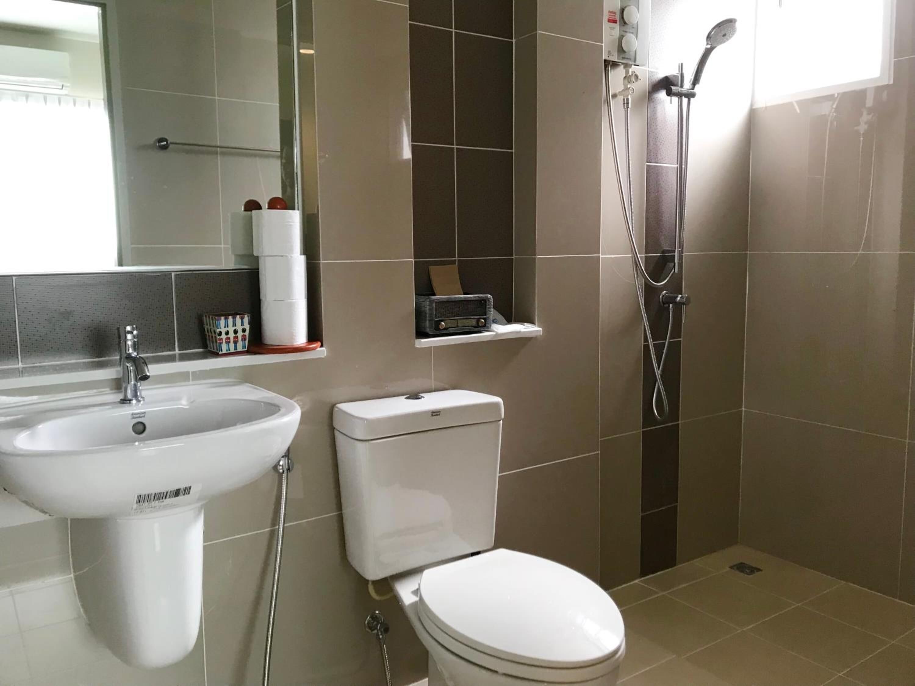 Et moderne badeværelse med vask, toilet og bruser.