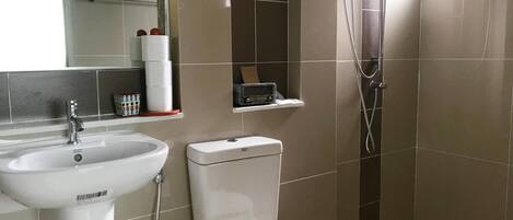 Et moderne badeværelse med vask, toilet og bruser.