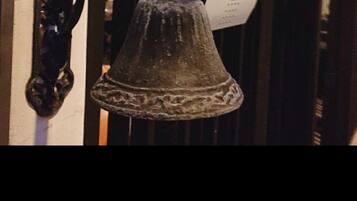 A decorative bell with two white birds on top, mounted on a wall.