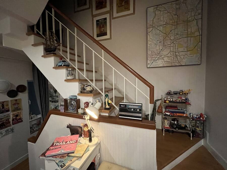 A staircase with a wooden handrail and white balusters, leading to a landing with a map on the wall.