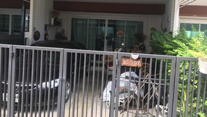 Een garage met woonruimte, een auto en een fiets, een bord met nummer '10/197', en een 'Kom binnen'-bordje op de deur.