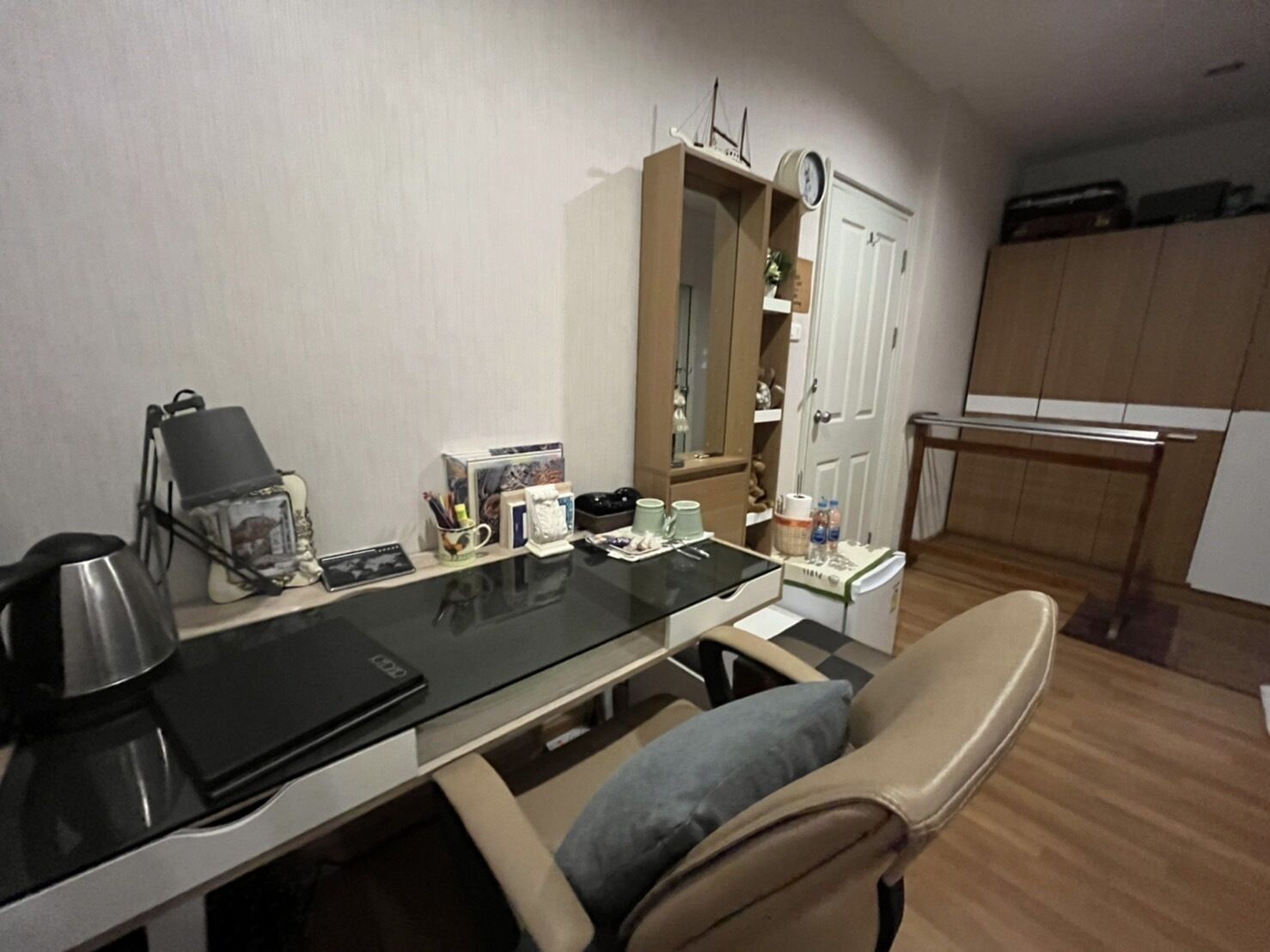 A compact living space with a kitchenette, a dining area with a glass table, and a seating area with a cushioned chair.