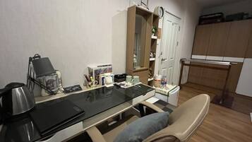 A compact living space with a kitchenette, a dining area with a glass table, and a seating area with a cushioned chair.