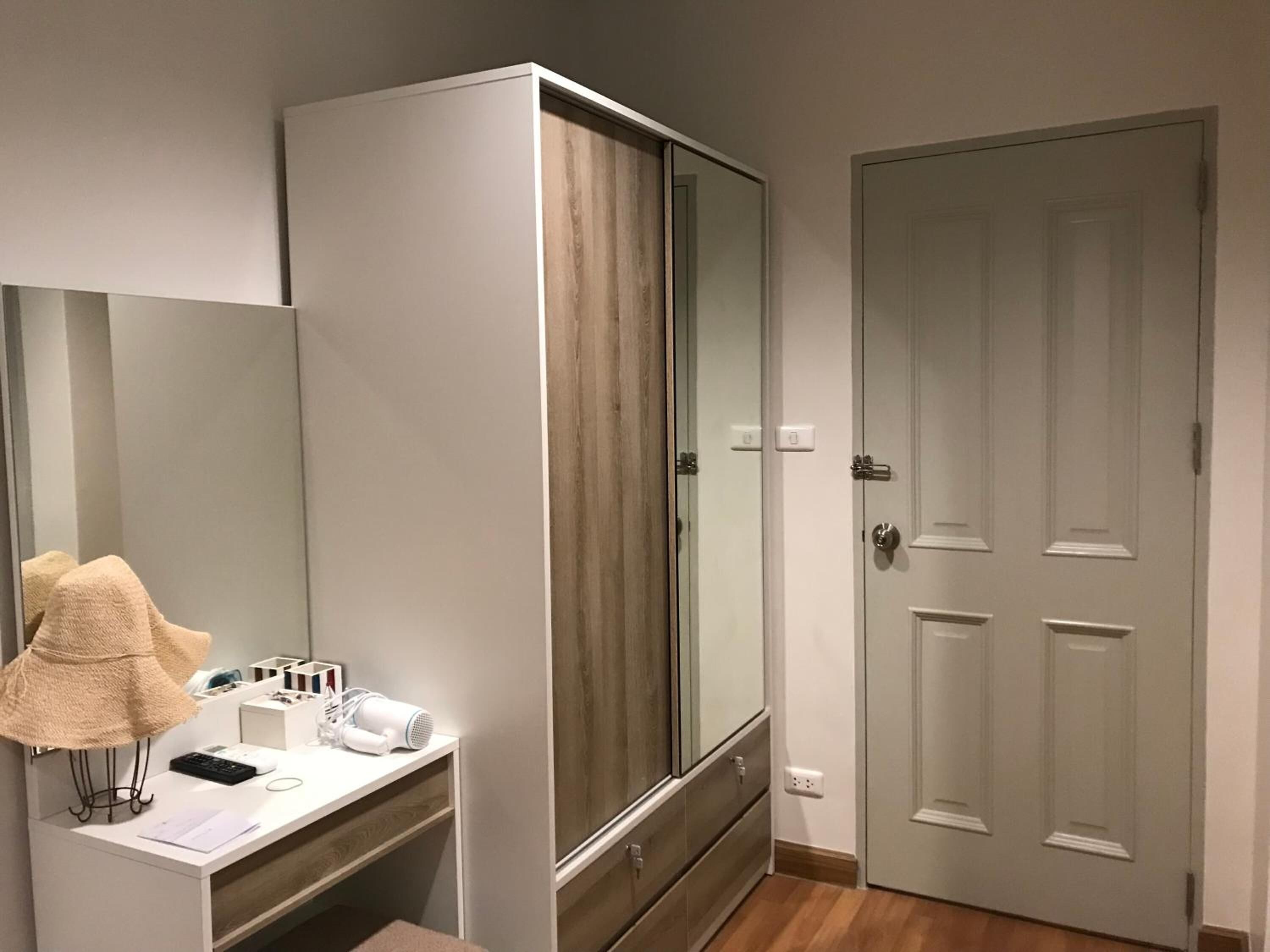 Une chambre avec une grande armoire, une coiffeuse avec un miroir et une porte.