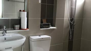 Um banheiro moderno com pia, vaso sanitário e chuveiro brancos.