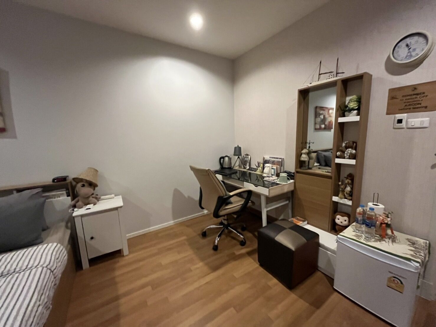 Ein Schlafzimmer mit Bett, Schreibtisch, Stuhl, kleinem Kühlschrank und Nachttisch.
