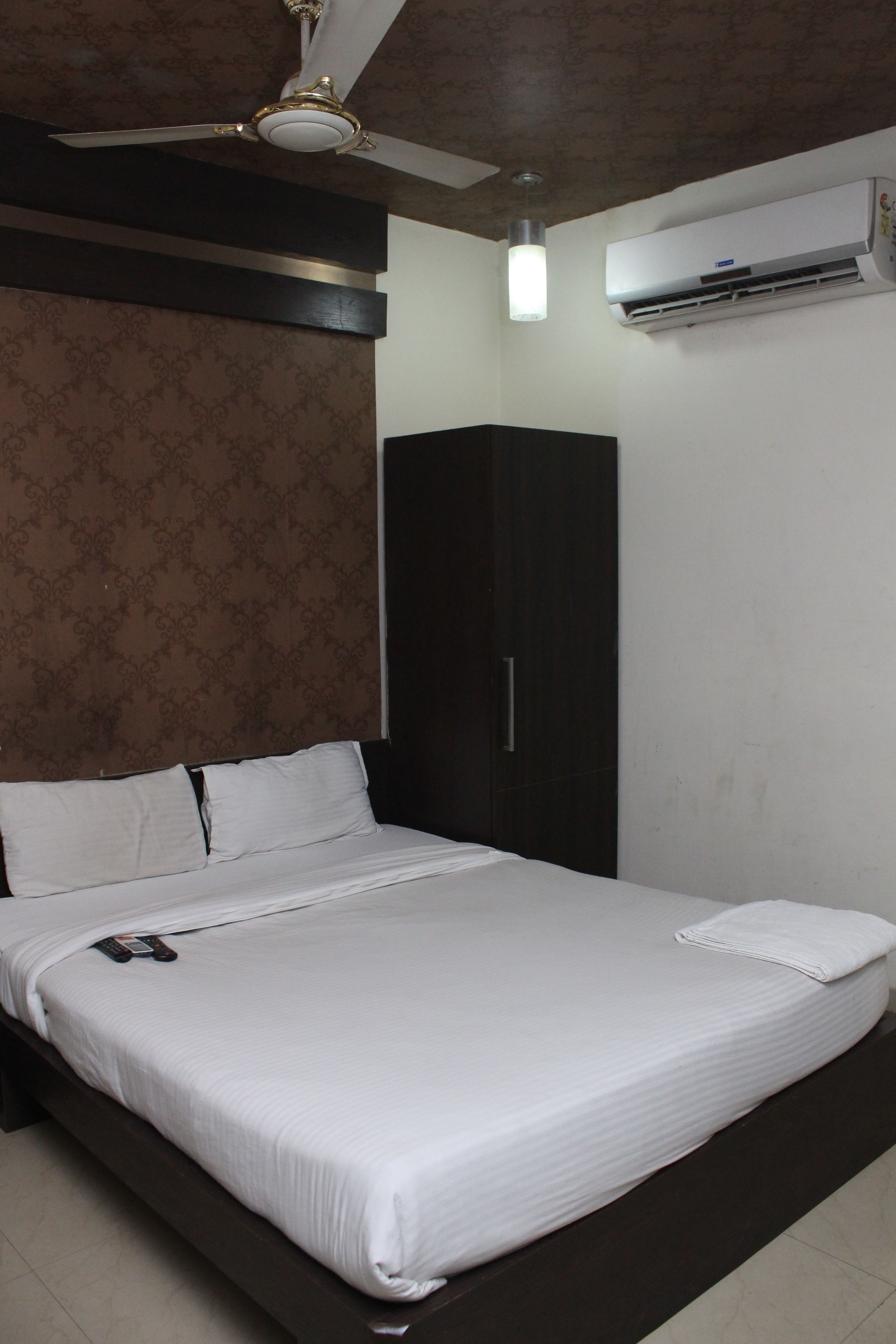 A neatly made bed with white linens, a dark wooden headboard, and a ceiling fan.