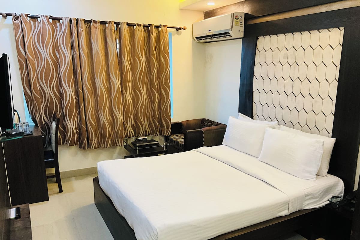 Una habitación de hotel con cama, mesita de noche, escritorio y silla.
