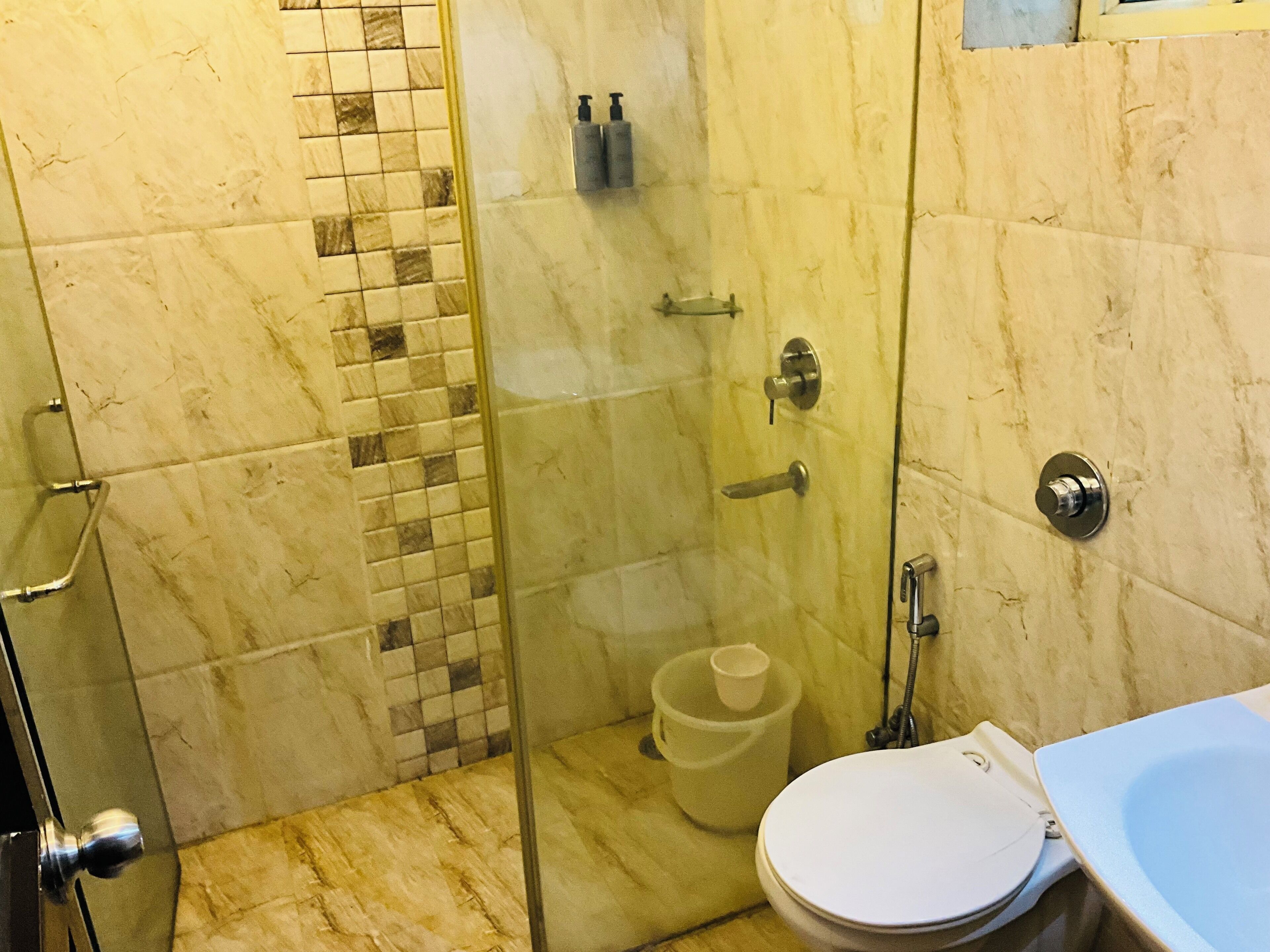 Un bany amb dutxa trencada per vidre, vàter i rentapans.