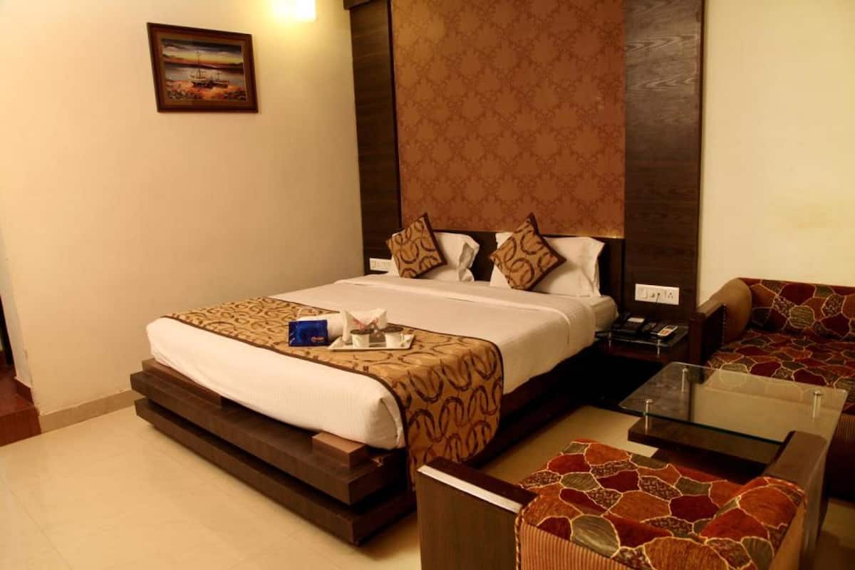 Una habitación de hotel con cama, mesita de noche, lámpara y sofá.