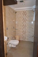 Un baño con inodoro, ducha y un panel decorativo en la pared.